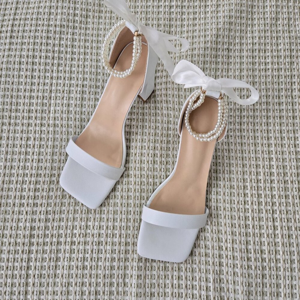Classic white heels with bow and pearls.